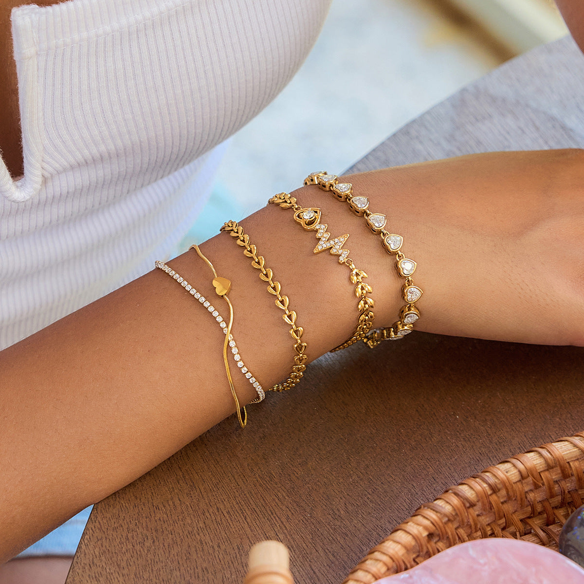 Close-up of a wrist wearing multiple gold bracelets on a blurred background