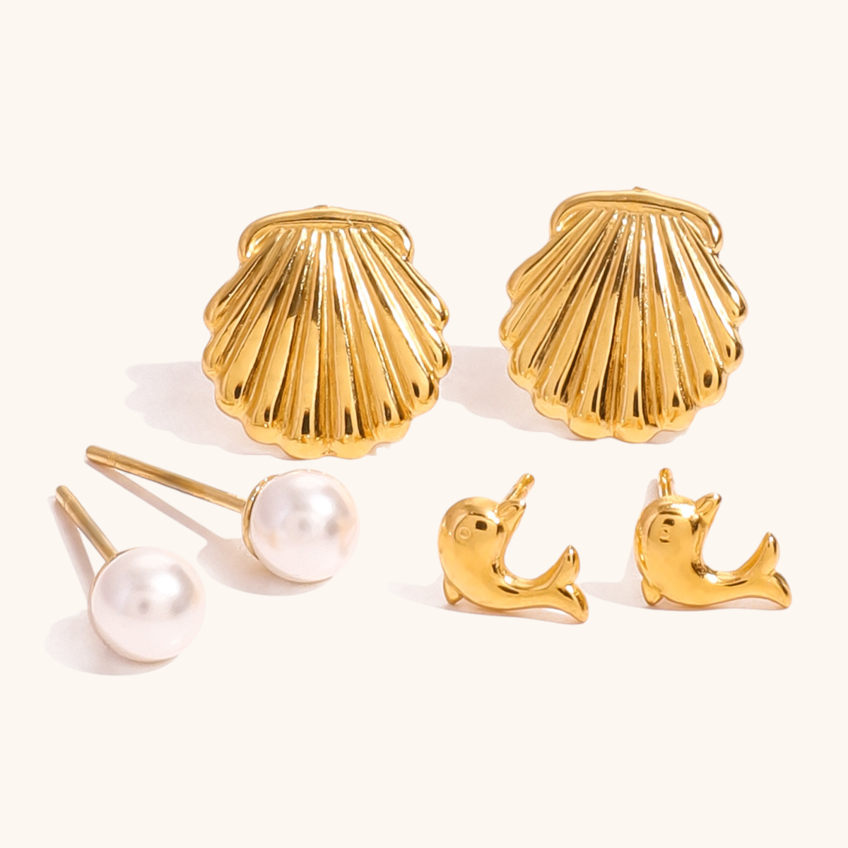 Gold dolphin earrings for women, ocean animal-inspired design on beige surface