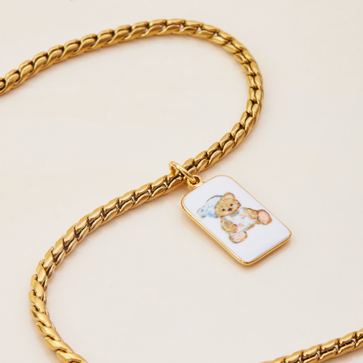 Rectangular bear charm hanging from sleek gold choker in studio lighting