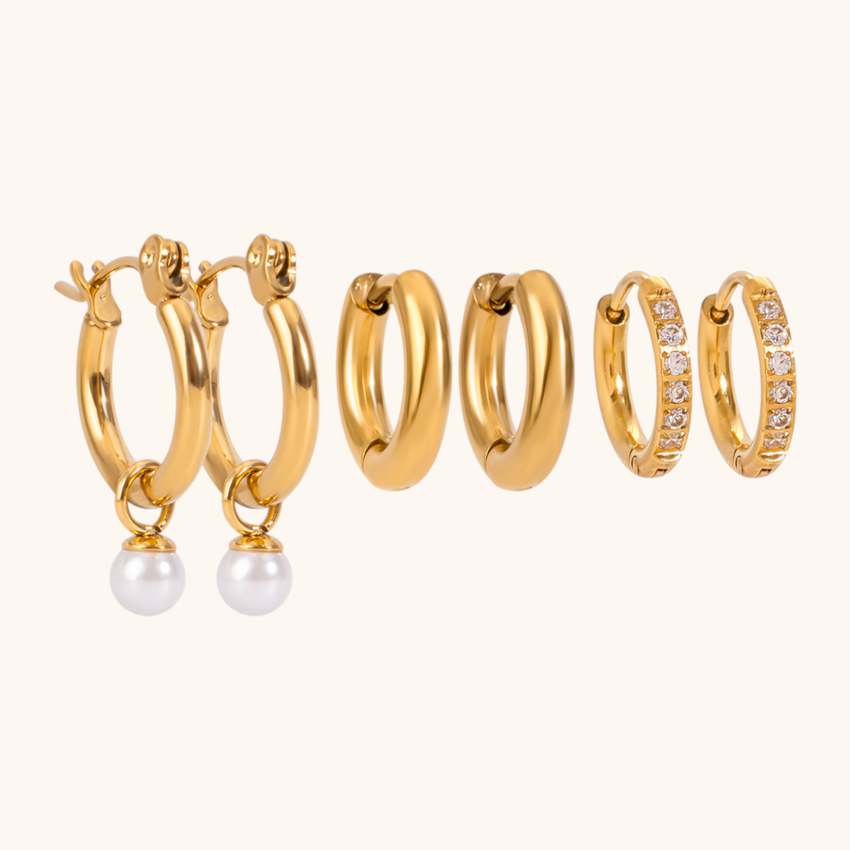 Set of 3 pairs of dainty gold hoop earrings with crystals and pearl accents, laid out in rows