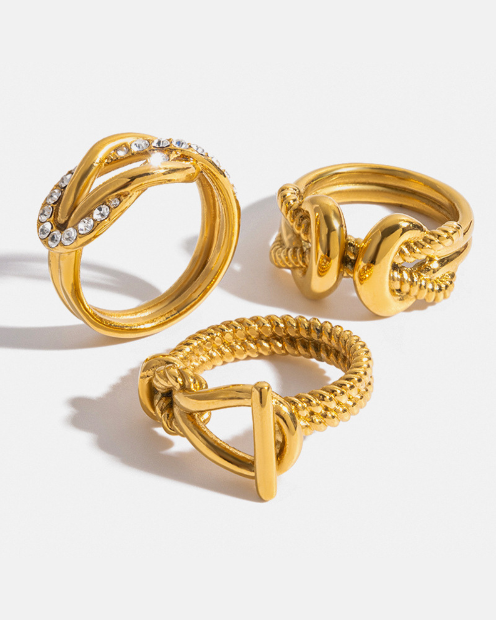 Three gold rings with intricate designs on a white background