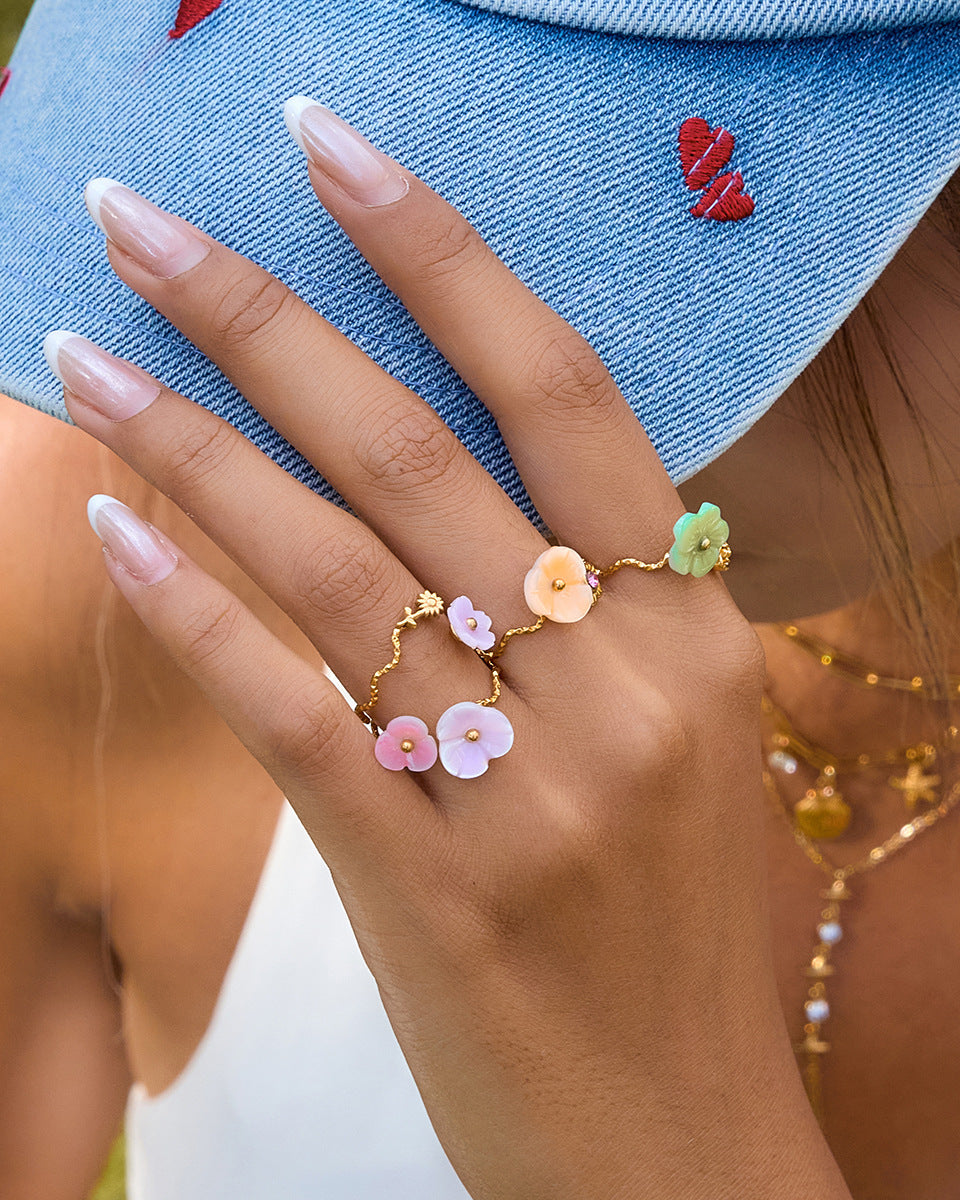 Hand wearing a floral ring with a denim background