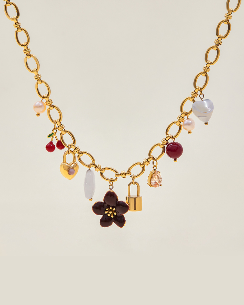 Gold necklace with various charms on a light beige background
