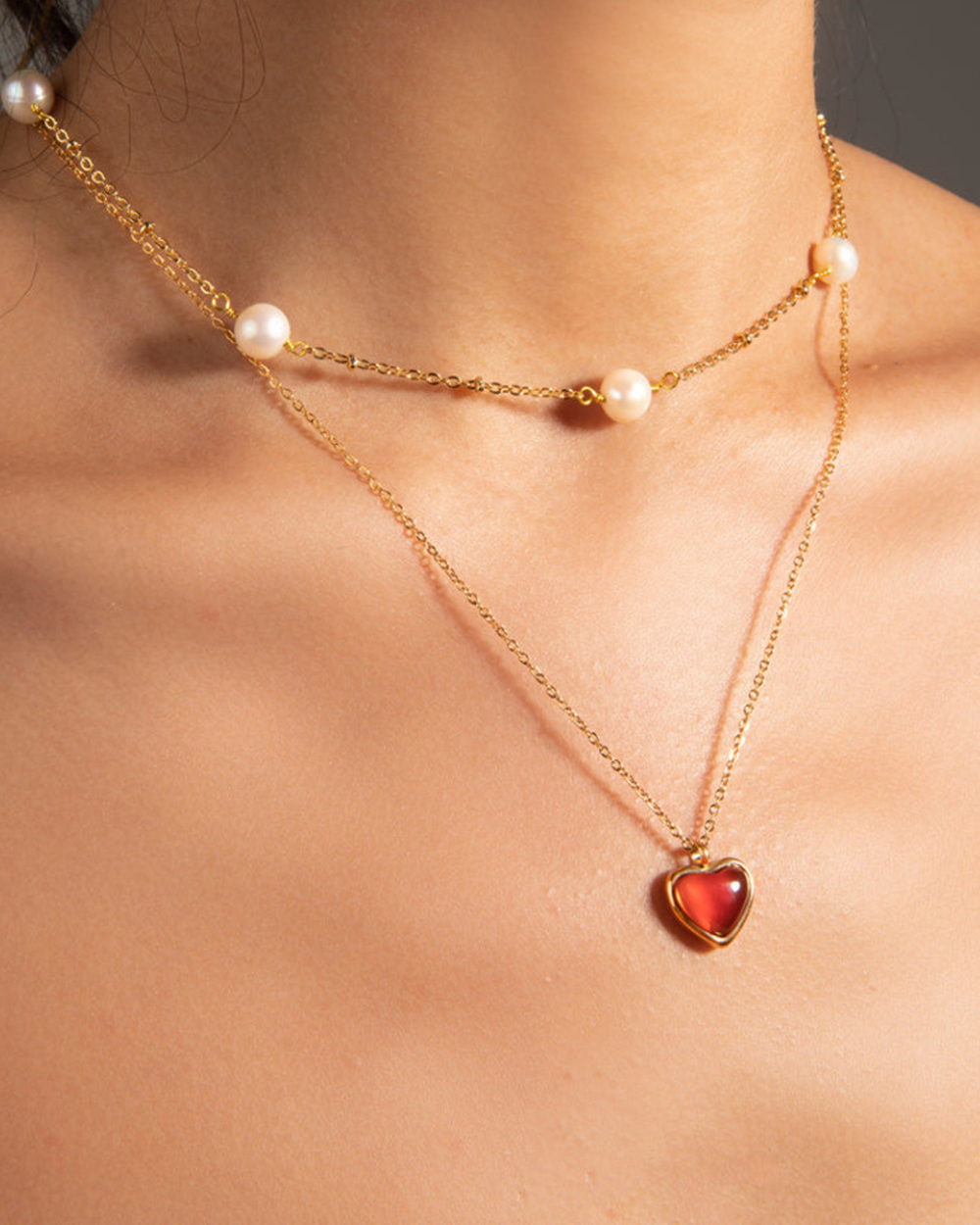 Gold necklace with a heart-shaped pendant on a person's neck