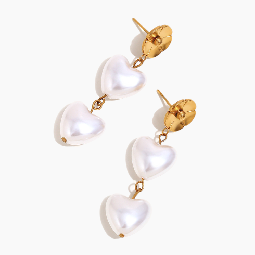 Heart-shaped pearl drop earrings displayed on soft neutral background