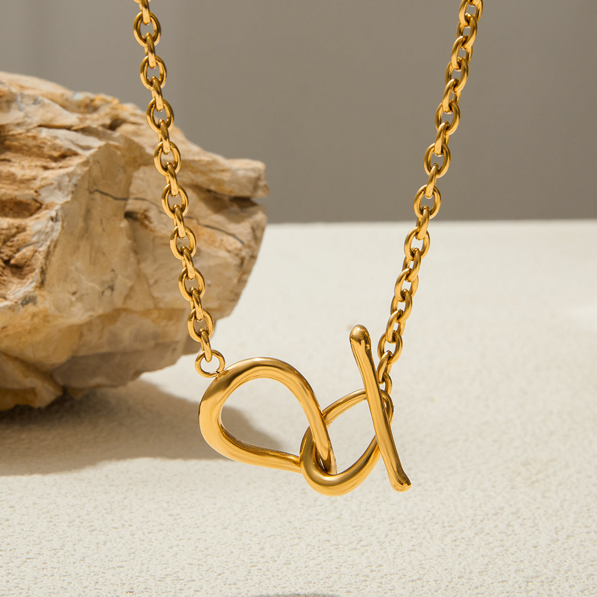 Gold necklace with a unique pendant design on a neutral background
