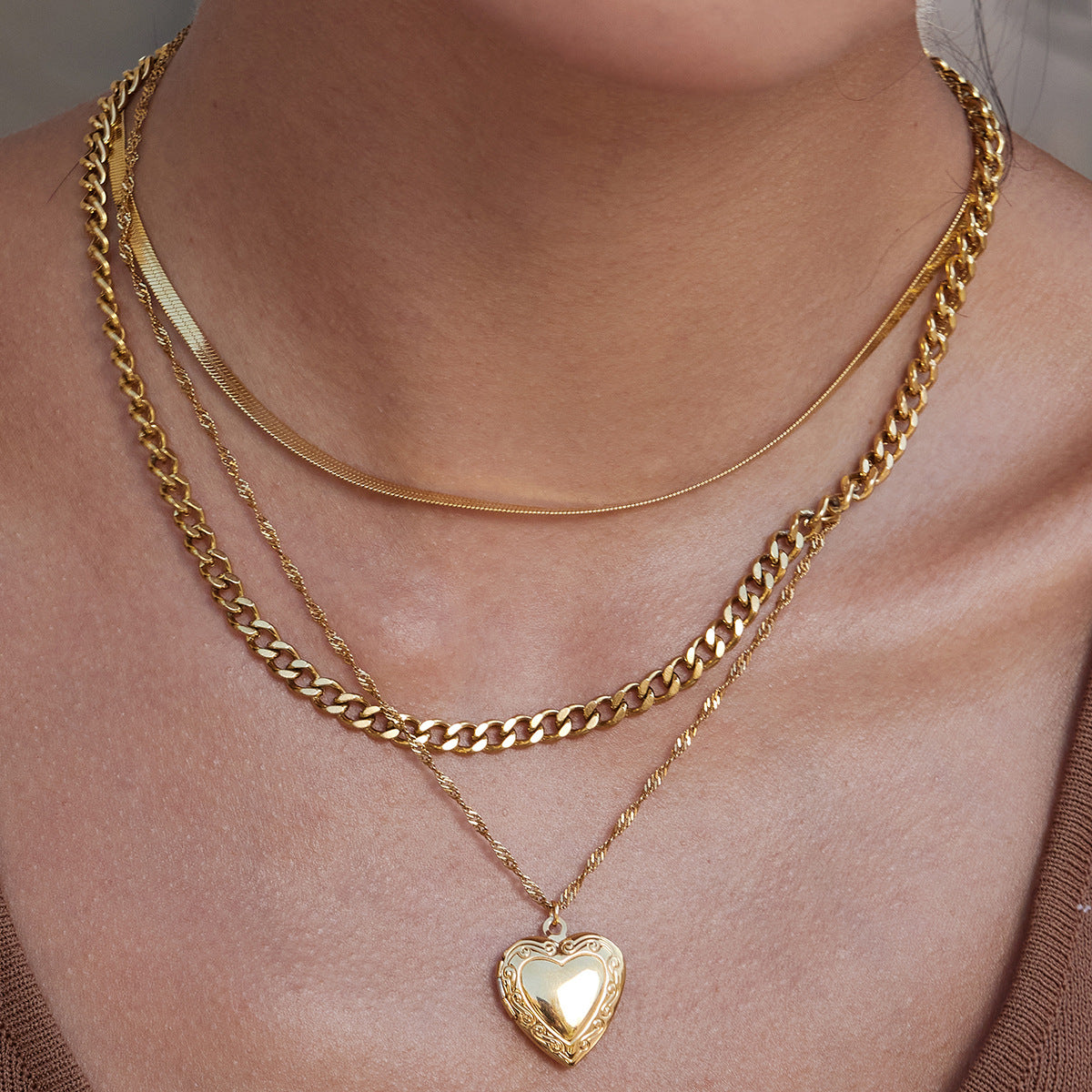 Close-up of a person wearing multiple gold necklaces with heart pendants.
