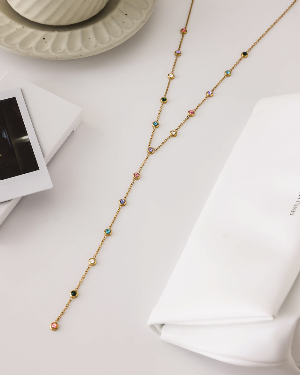 Gold necklace with colorful beads on a white surface