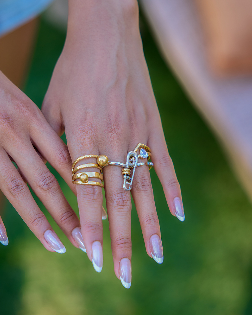 Close-up of hands with multiple rings on a blurred green background