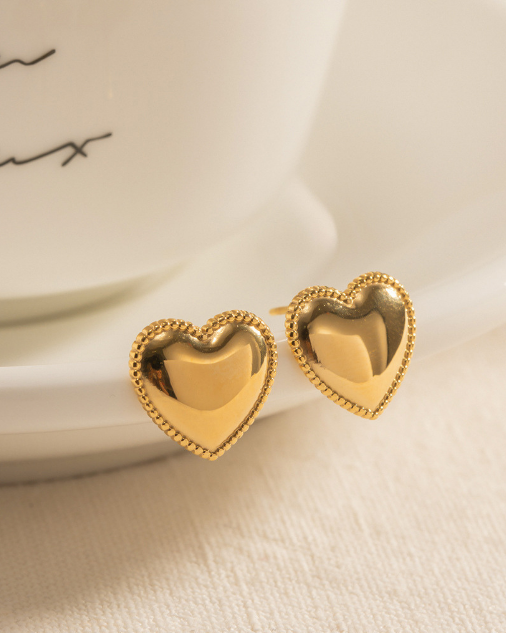 Gold heart-shaped earrings on a light background