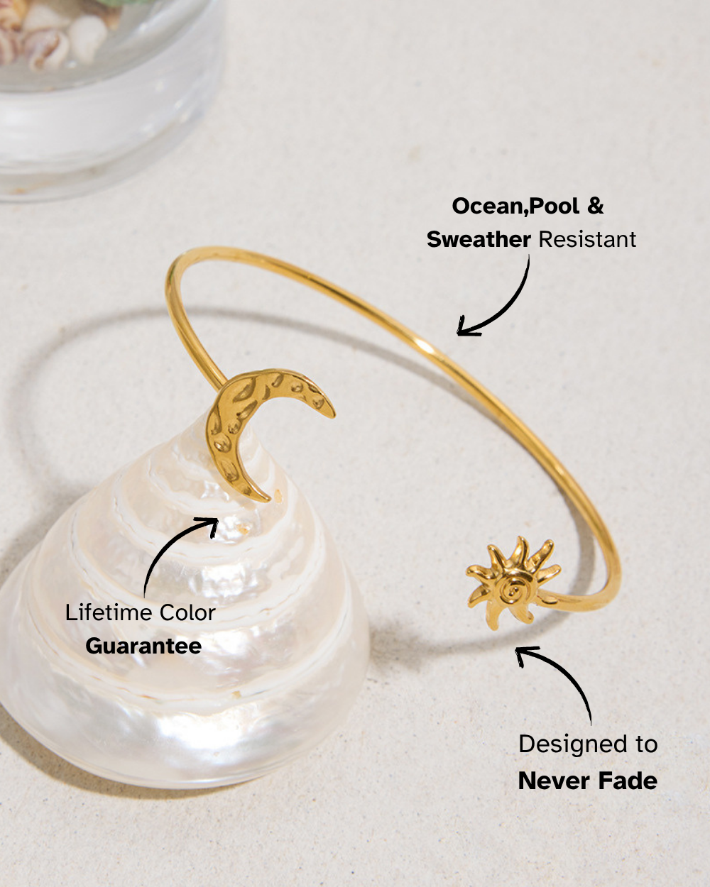 Gold bracelet with sun and moon designs on a shell with sand background