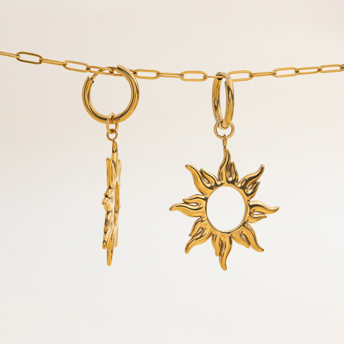 Pair of waterproof gold sun earrings hanging on a chain