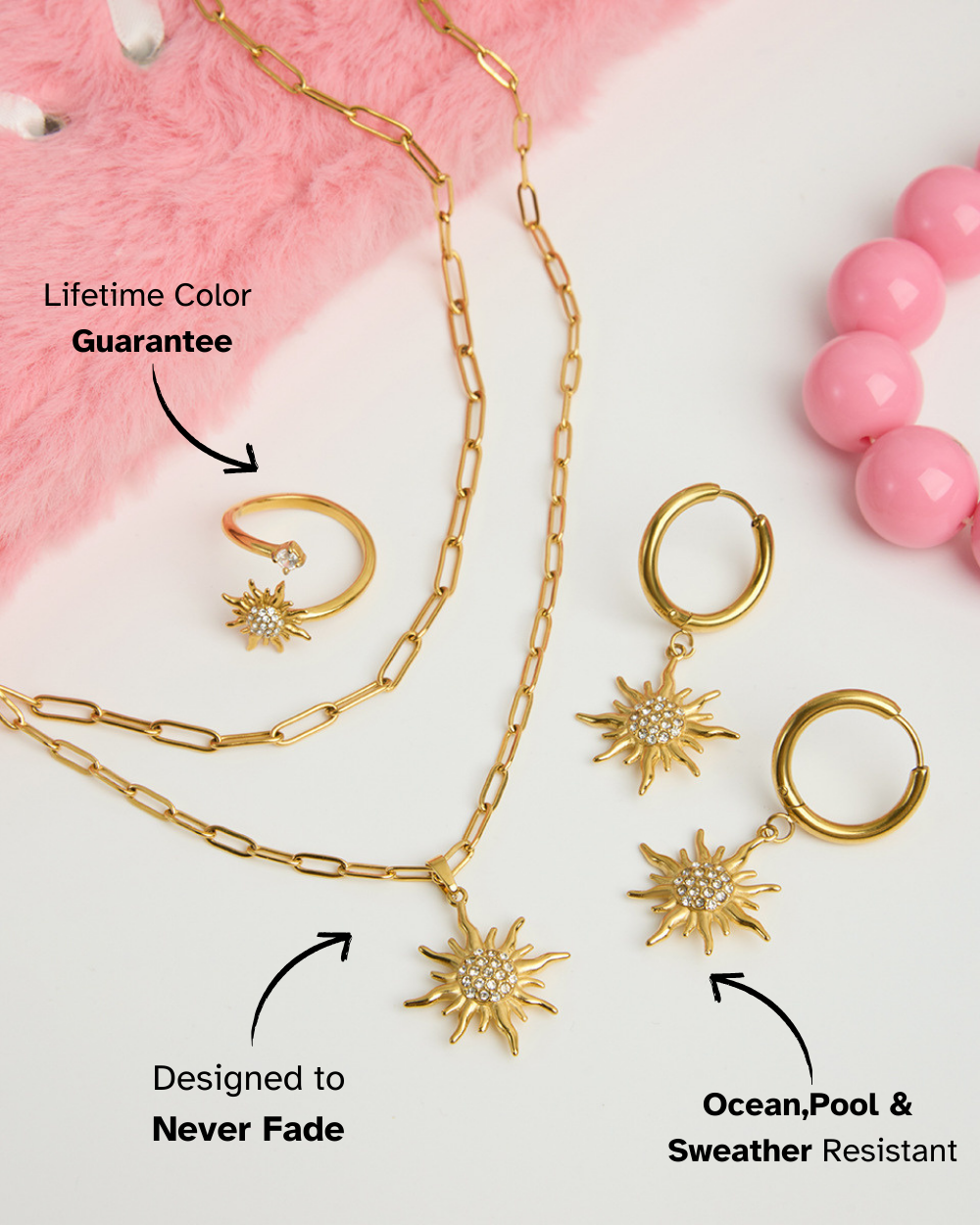 Gold jewelry set with necklaces, rings, and earrings on a pink and white background.