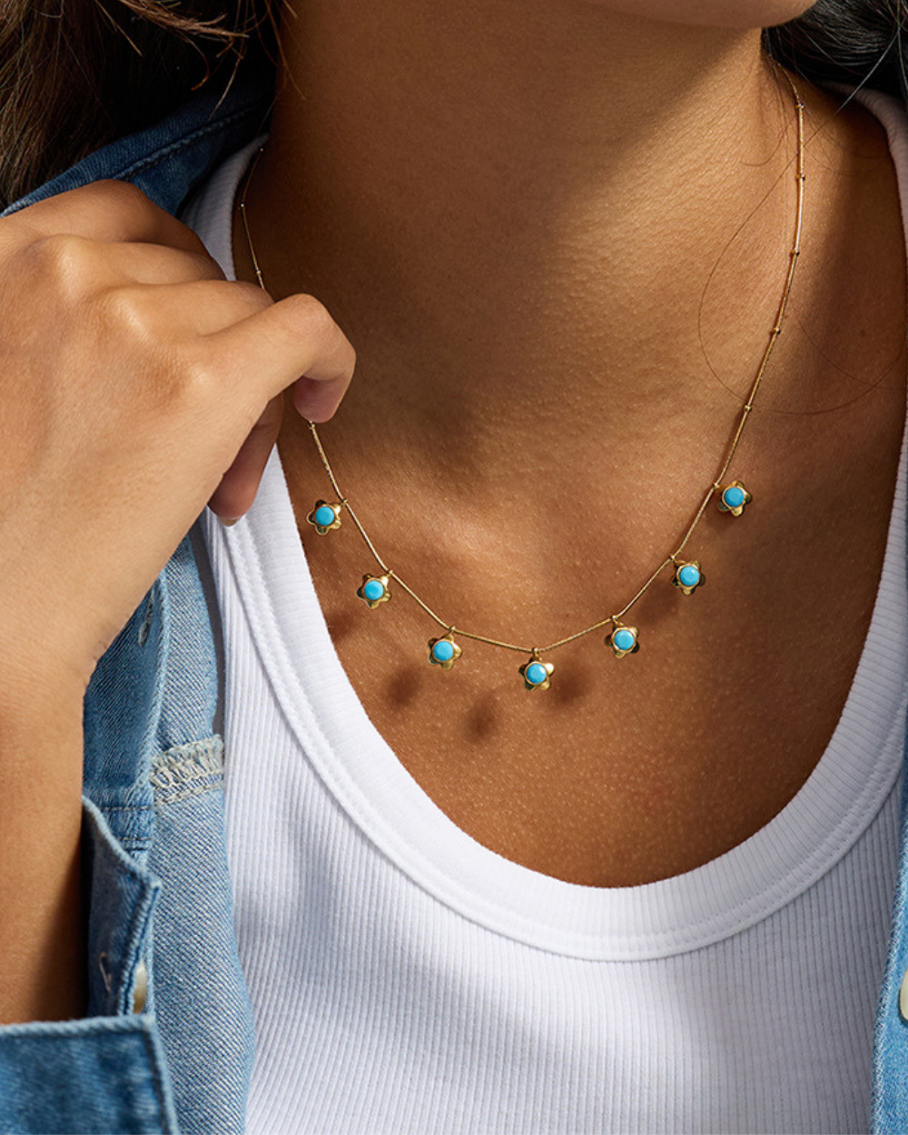 Necklace with turquoise stones worn by a person, close-up view.