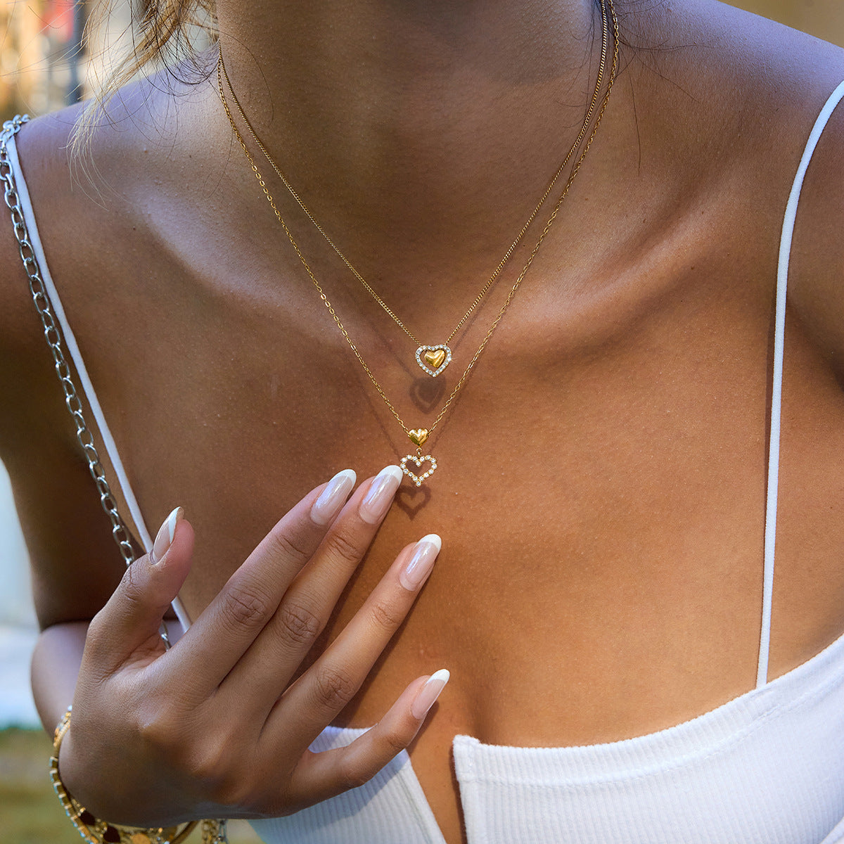 Gold necklace with heart pendants worn by a person outdoors