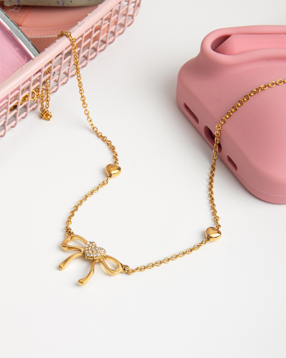 Gold necklace with a bow pendant on a white background