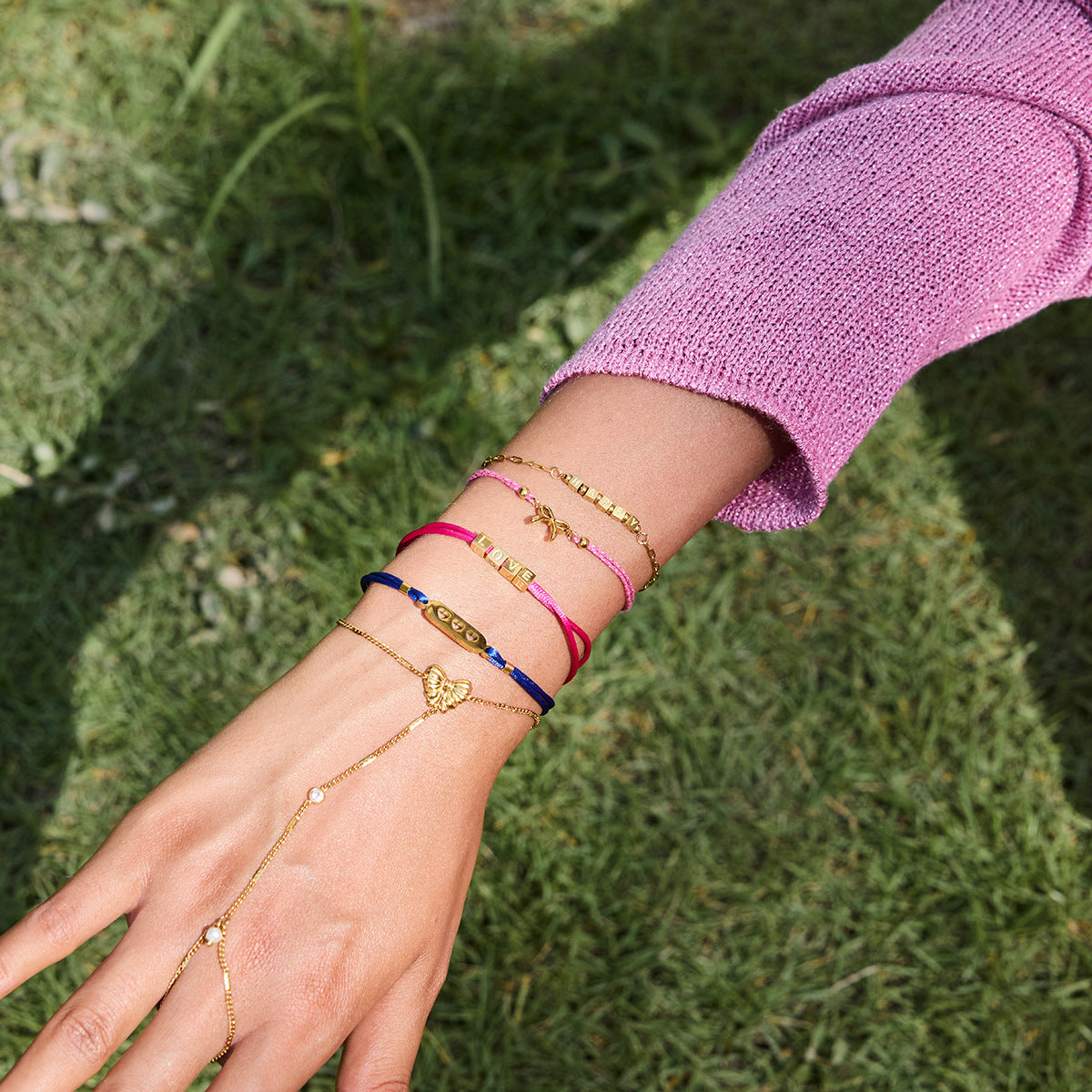 Hand wearing multiple bracelets on a grassy background