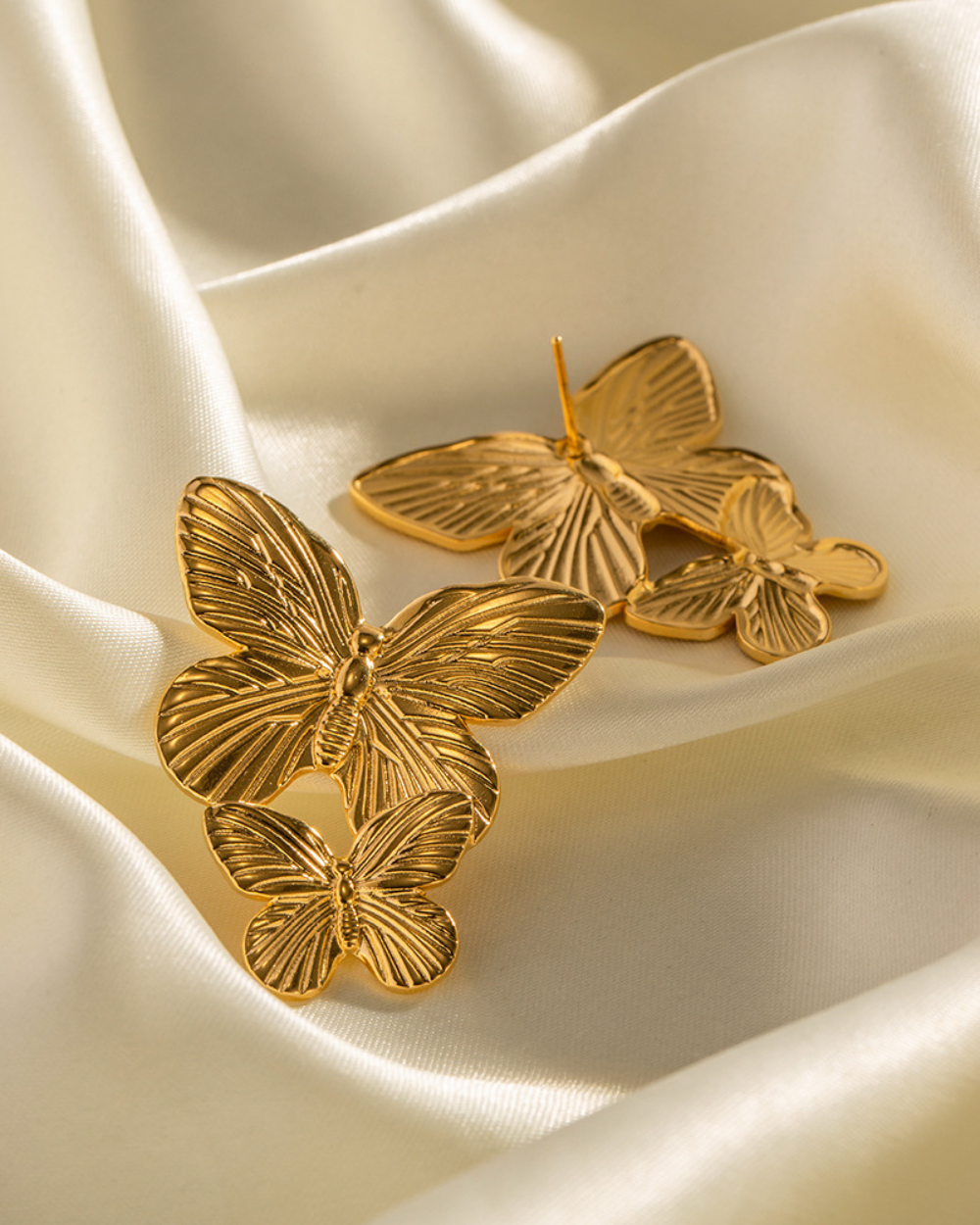 Gold butterfly-shaped jewelry on a beige fabric background