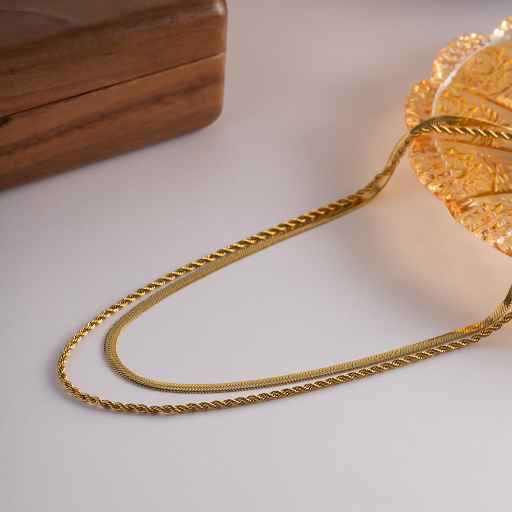 Layered necklace resting beside a vintage glass dish and jewelry box in soft lighting