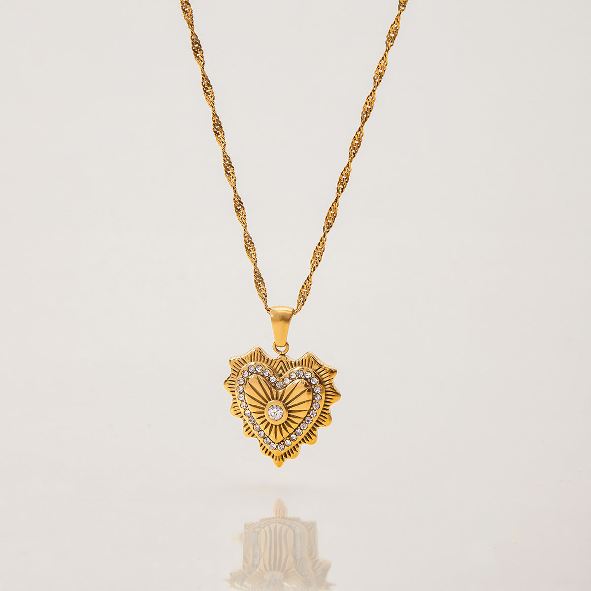 Close-up of double pendant gold necklace featuring vintage heart and crystal bar charms