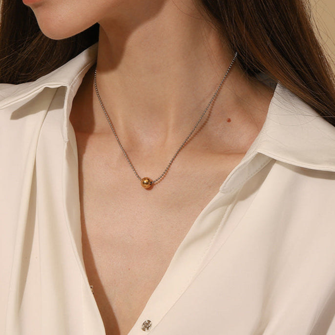 Model wearing dual tone gold and silver bead necklace with minimalist charm