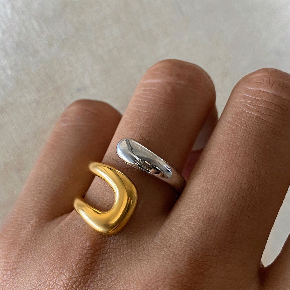 Gold and silver open ring worn on hand, showcasing its bold and modern design.