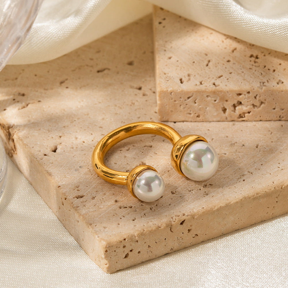 Gold open ring with two pearls on beige stone background