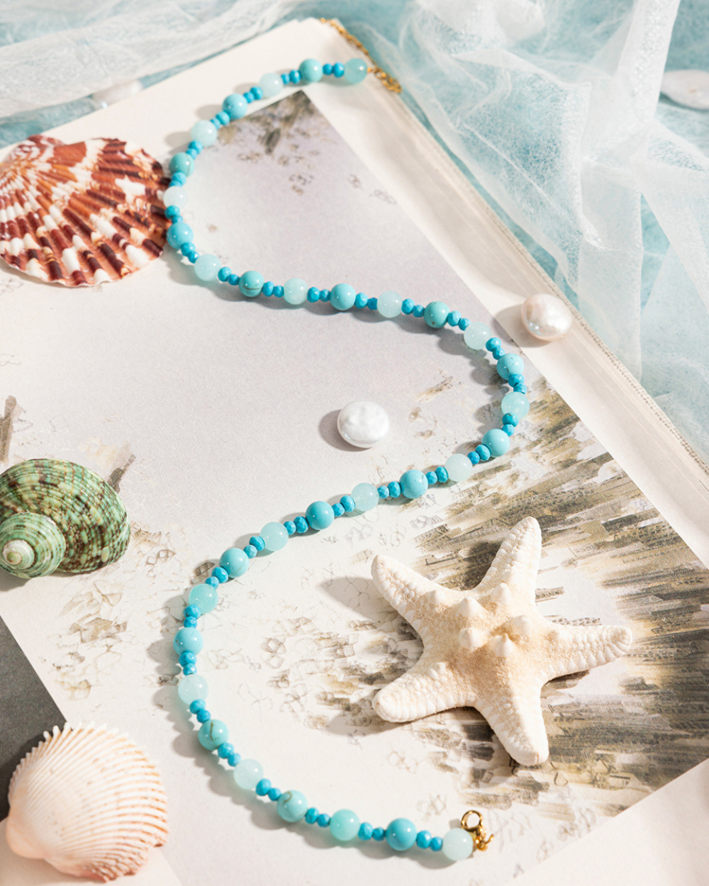 Turquoise beaded necklace with starfish and shells on a wooden surface