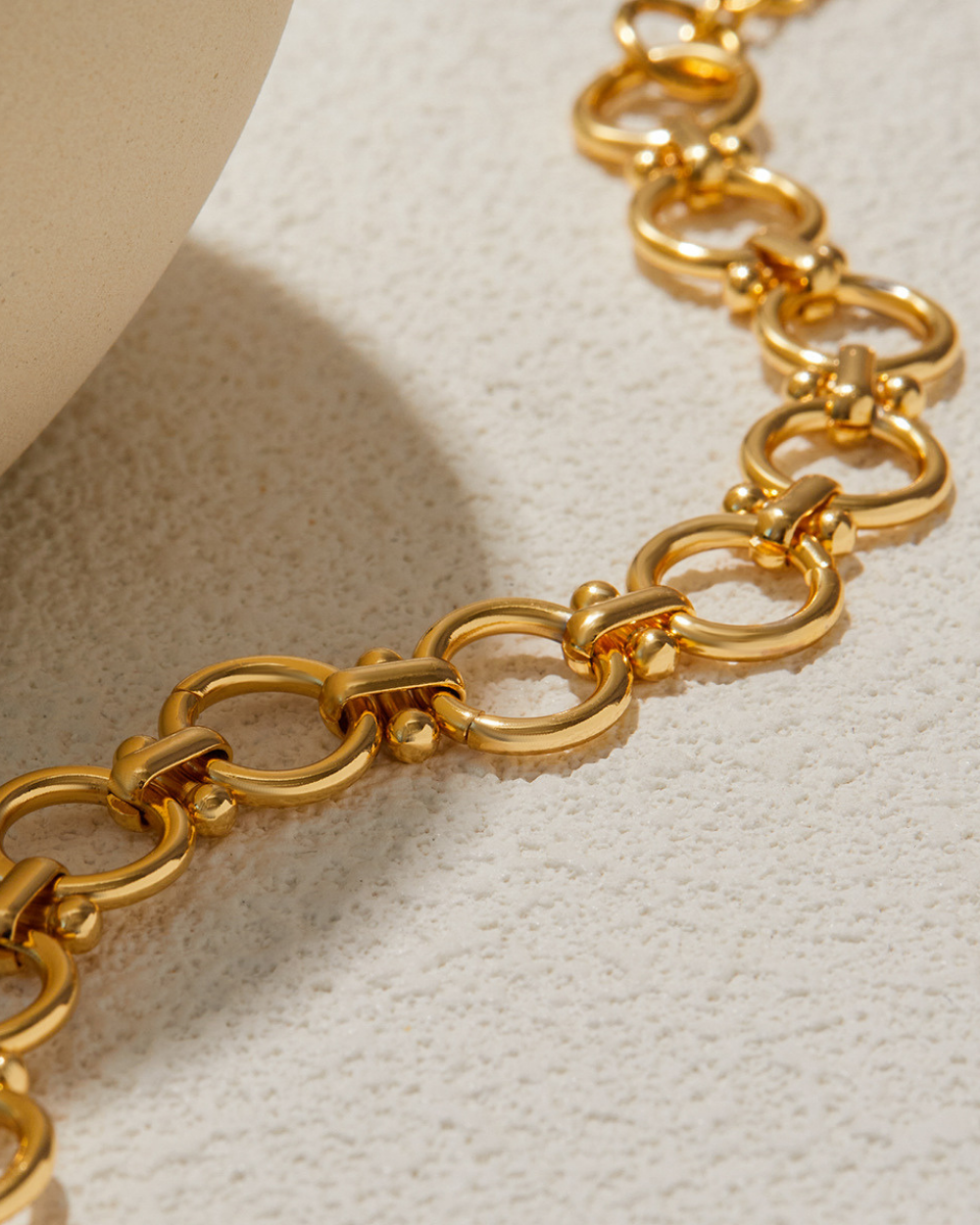 Gold chain necklace on a textured beige surface
