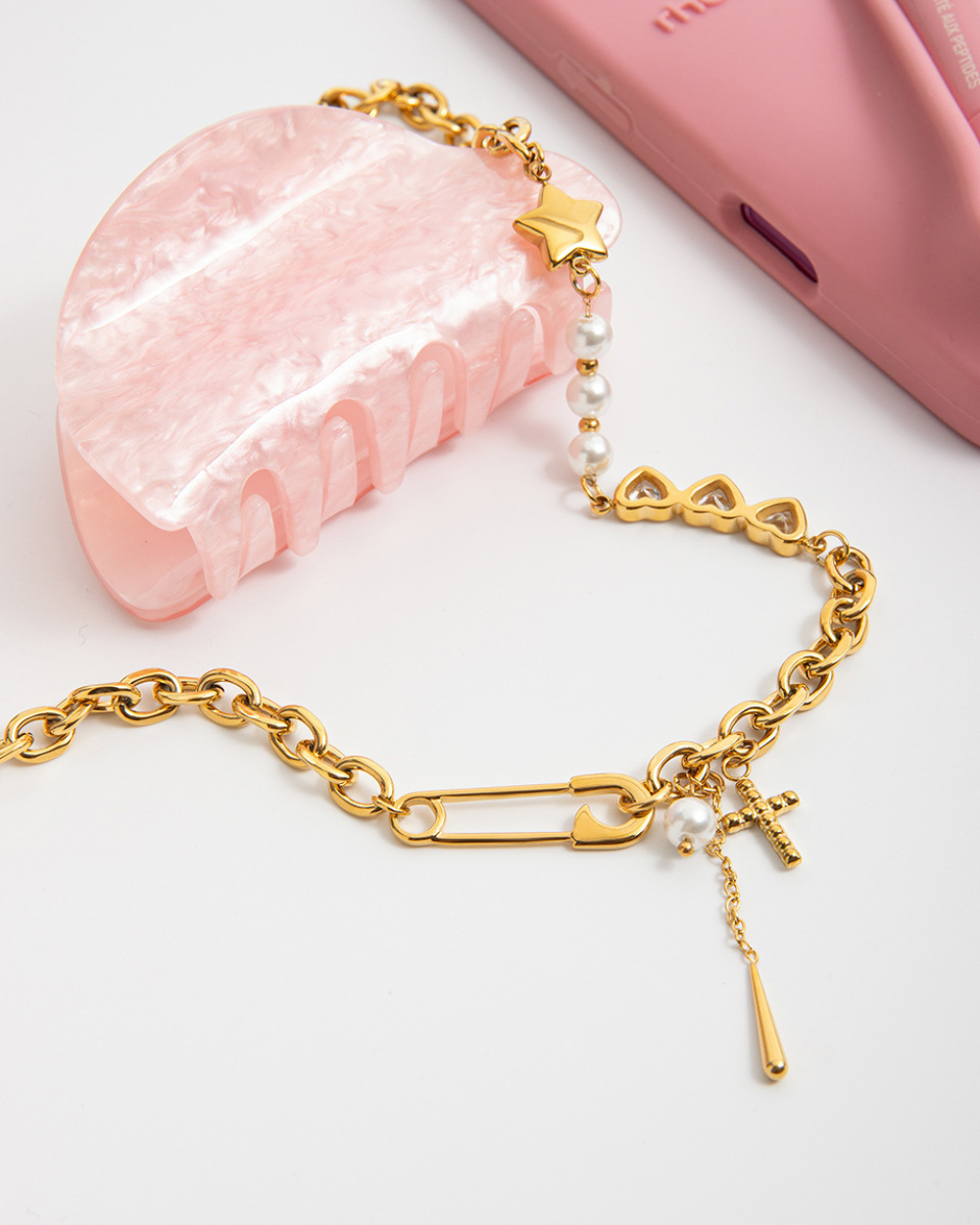 Gold bracelet with heart and star charms on a white background