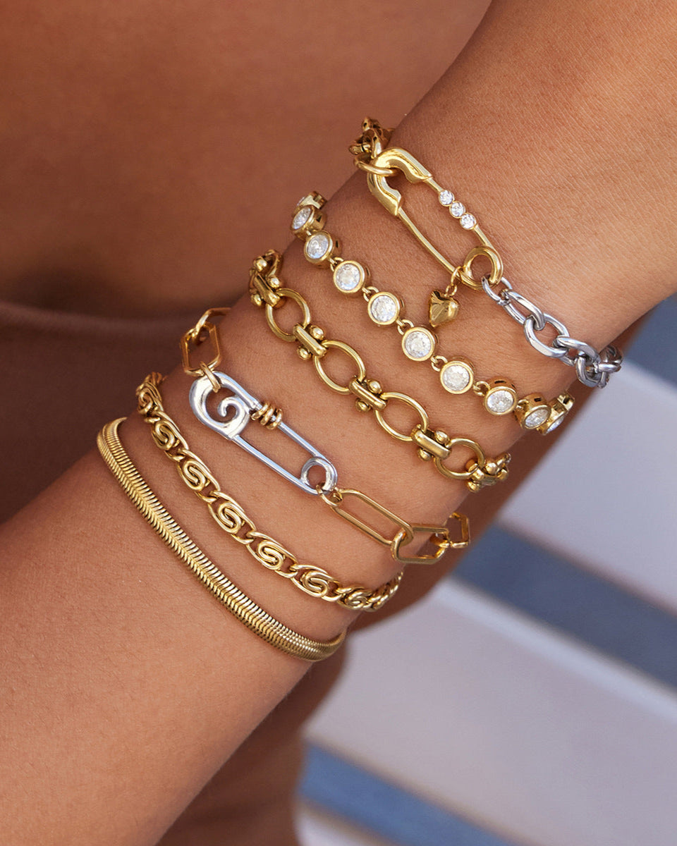 Close-up of a wrist wearing multiple gold and silver bracelets with a blurred background