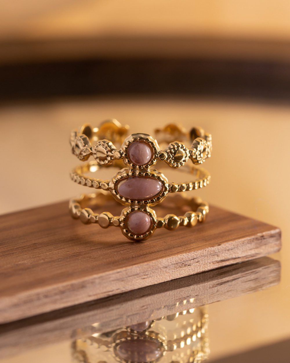 Set of gold rings with pink stones on a wooden surface