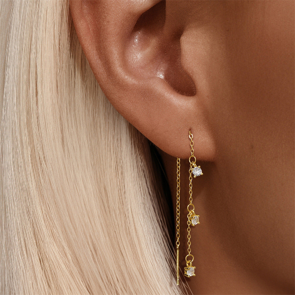 Model wearing long gold threader earrings with cubic zirconia drops for a minimalist glam look