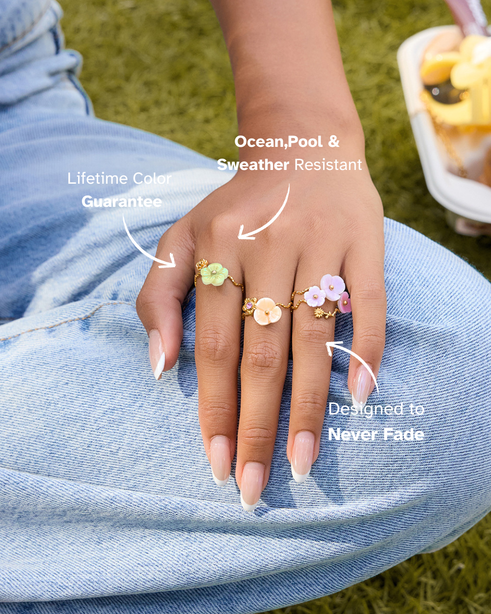 Hand wearing multiple floral rings with text highlighting features on a grassy background