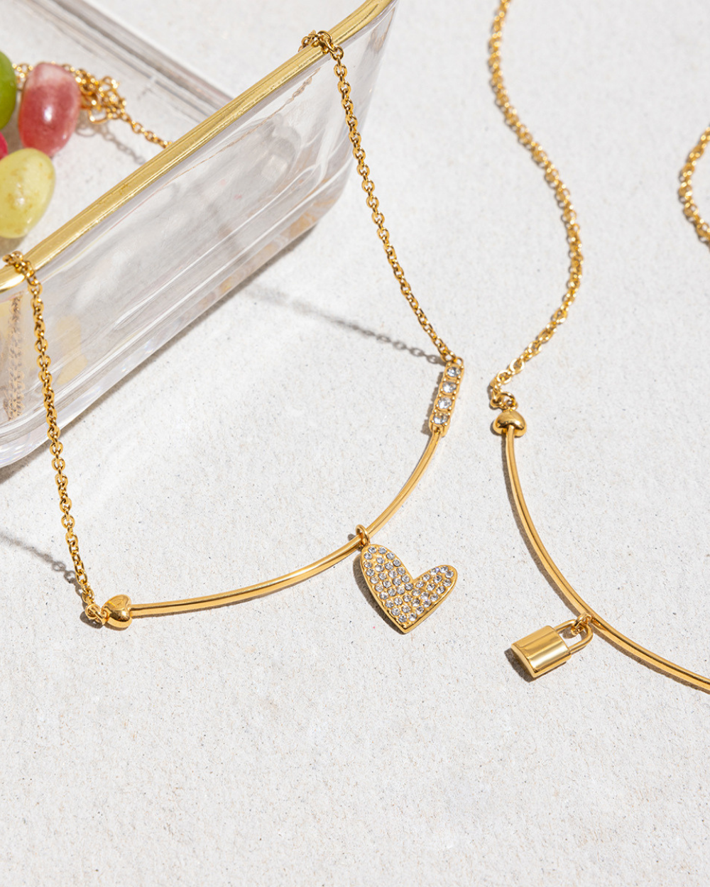 Gold necklace with a heart-shaped pendant on a light background
