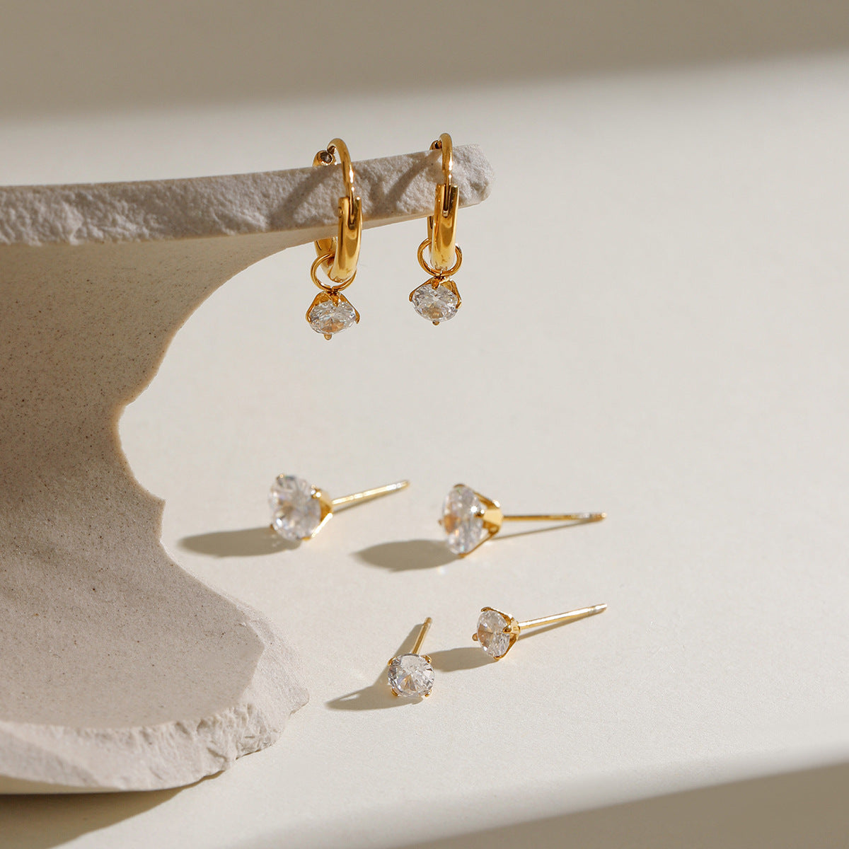 Minimalist gold earrings set featuring round-cut zirconia hoops and multiple size studs