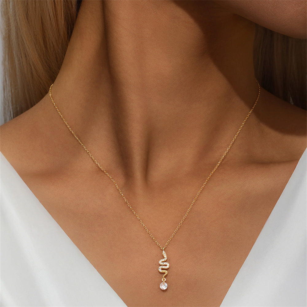 Gold snake necklace with zircon pendant worn by woman in white blouse, perfect for minimal chic look