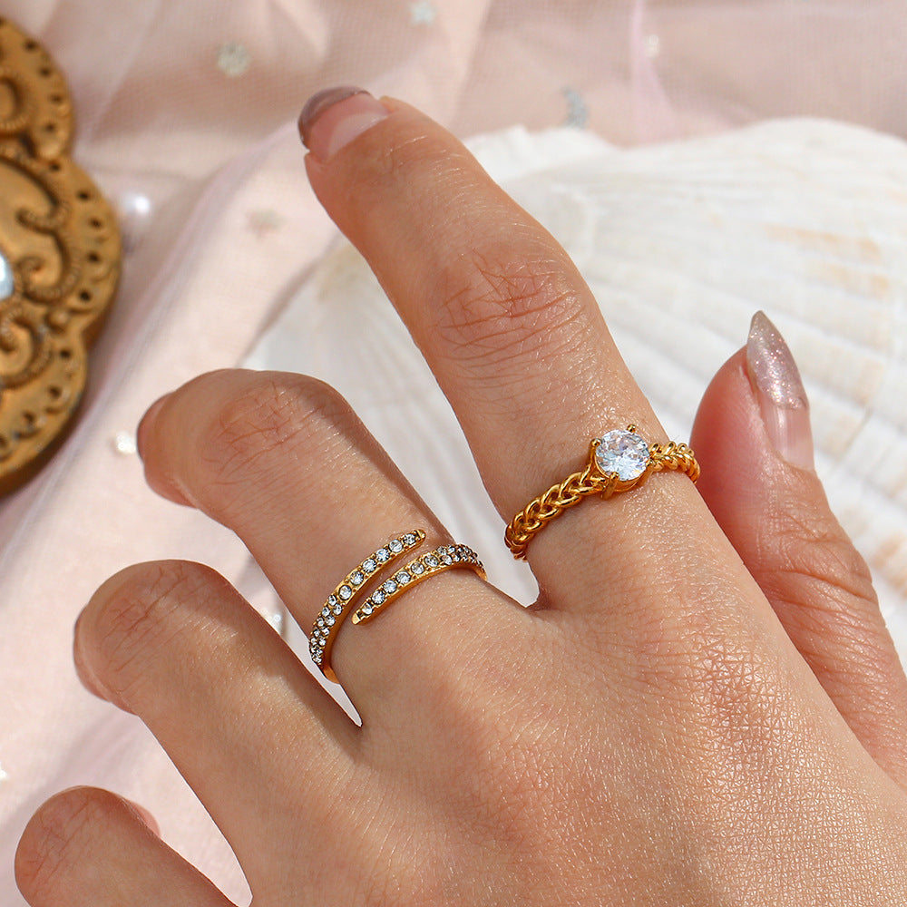 Gold crystal ring styled on hand with other gold rings on beach-inspired backdrop