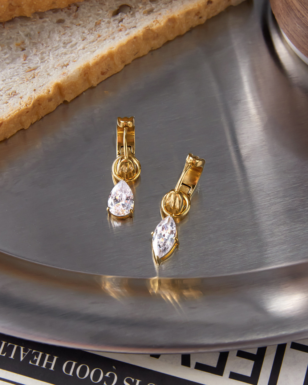 Gold earrings with clear stones on a metallic surface