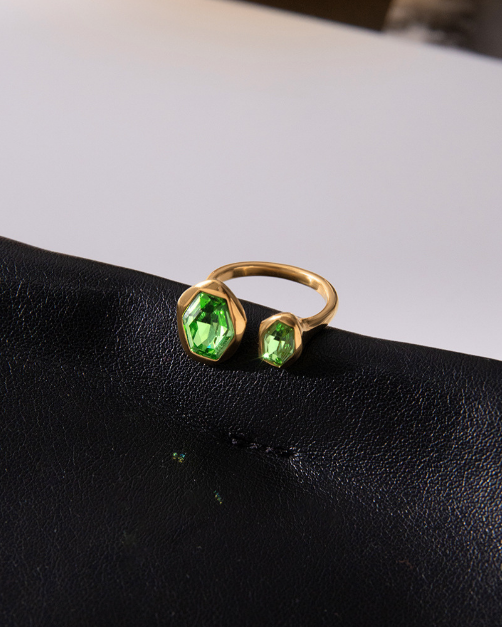 Gold ring with green gemstones on a black surface