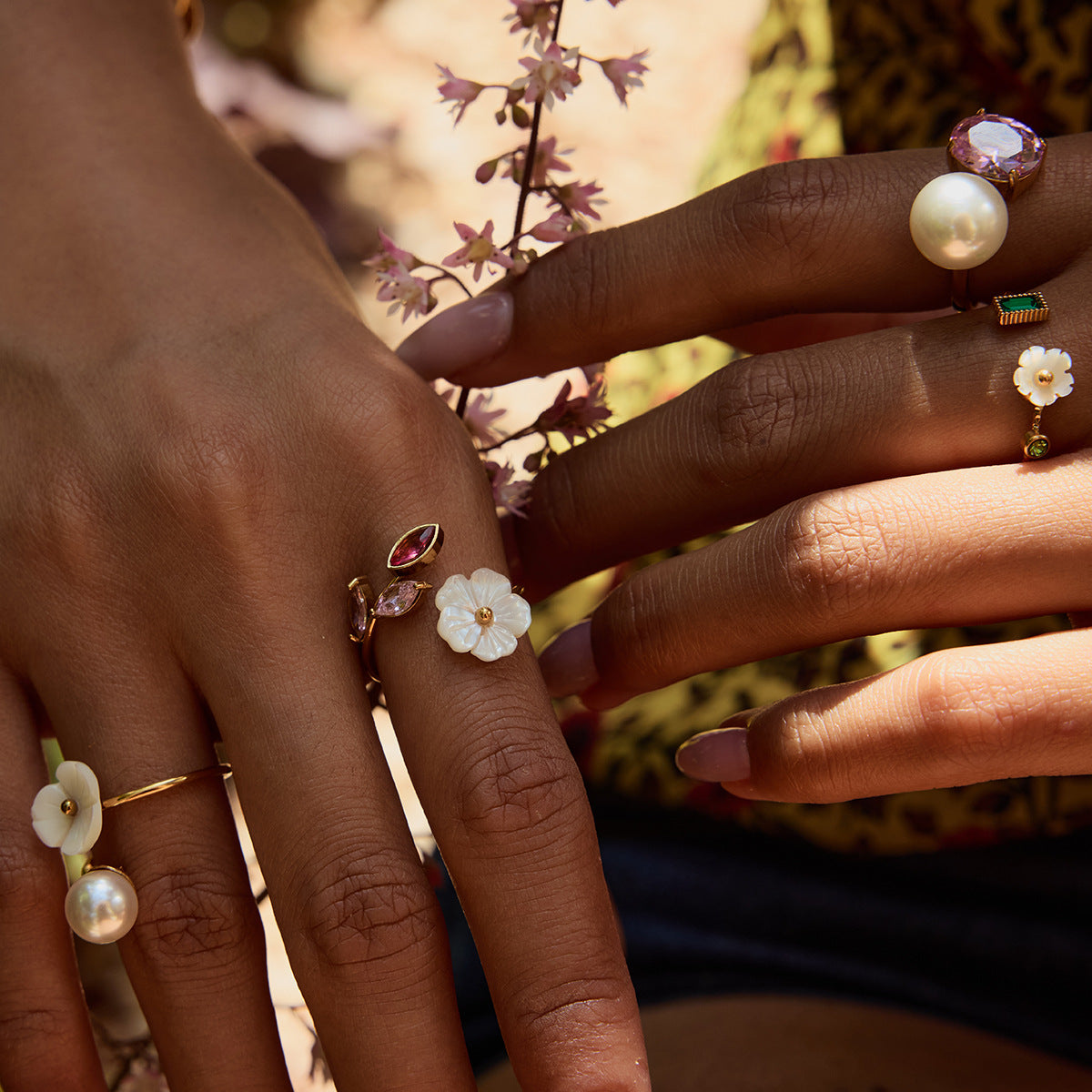 Layered floral rings on hand holding wildflowers outdoors