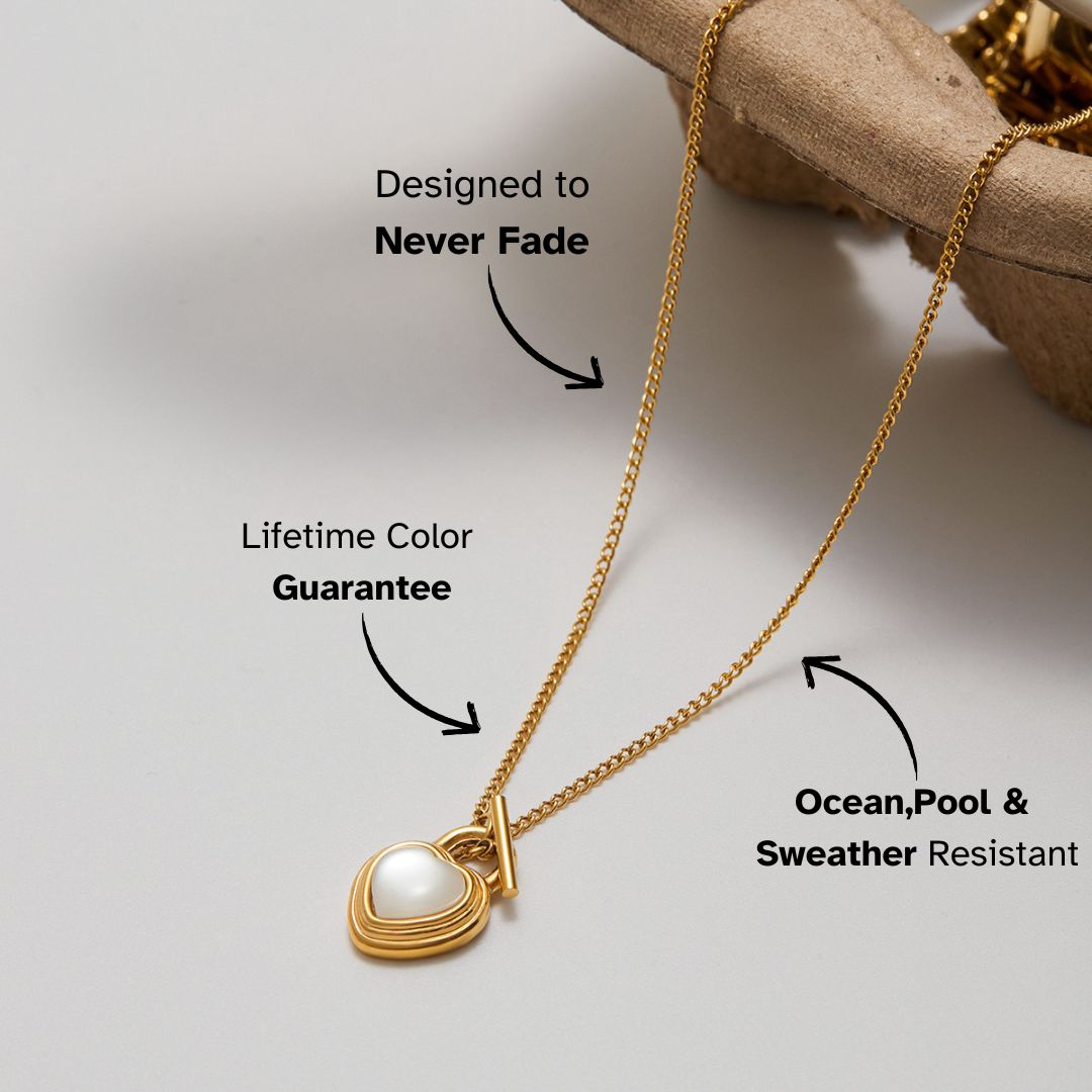 Gold heart pendant necklace with pearl center, shown close-up on neutral background