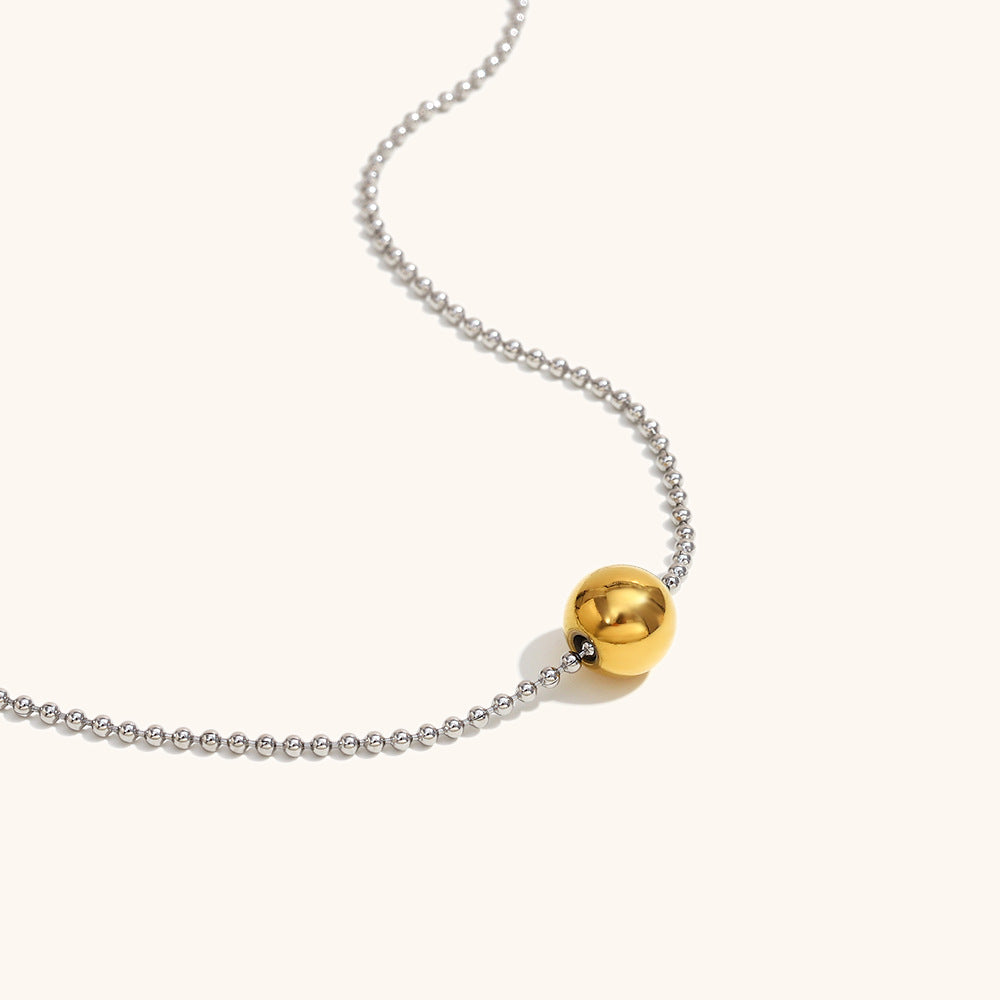 Delicate mixed metal necklace with gold sphere on silver chain, studio shot