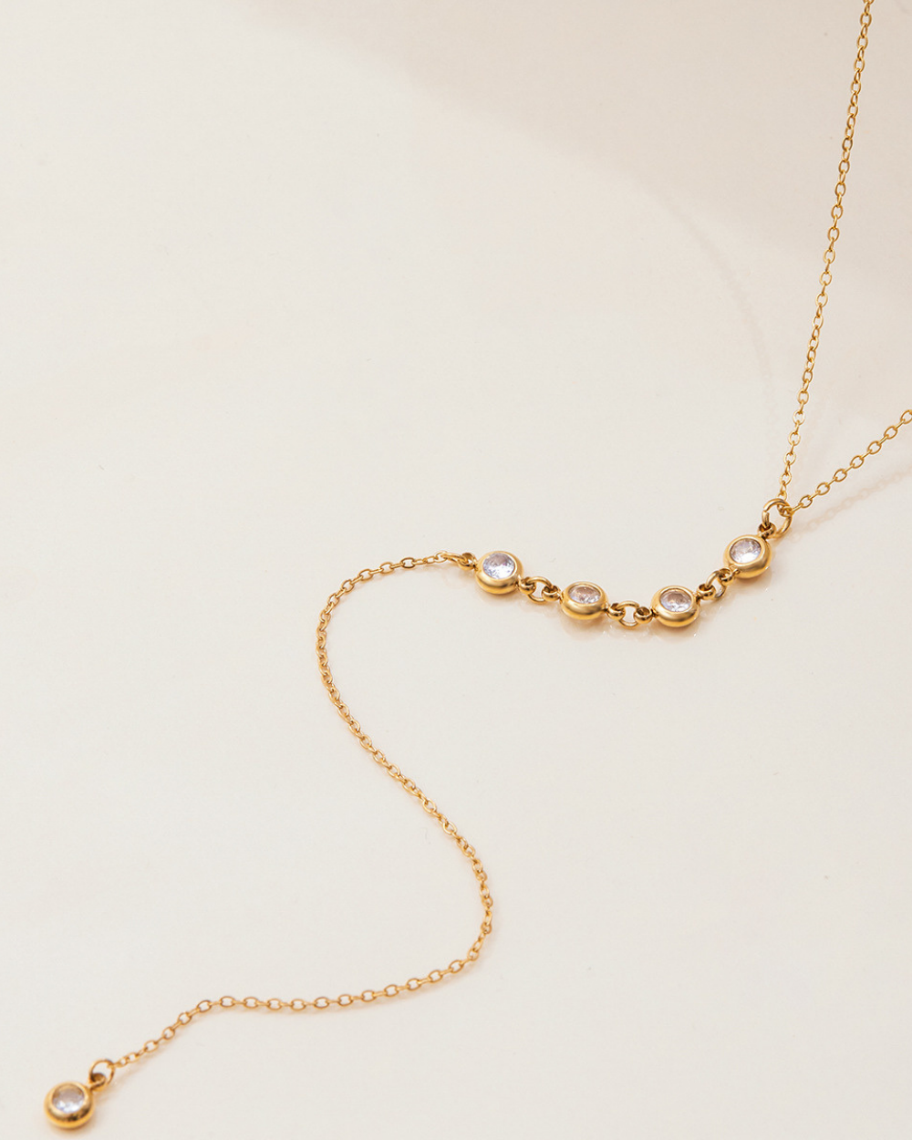 Gold necklace with small round pendants on a beige background
