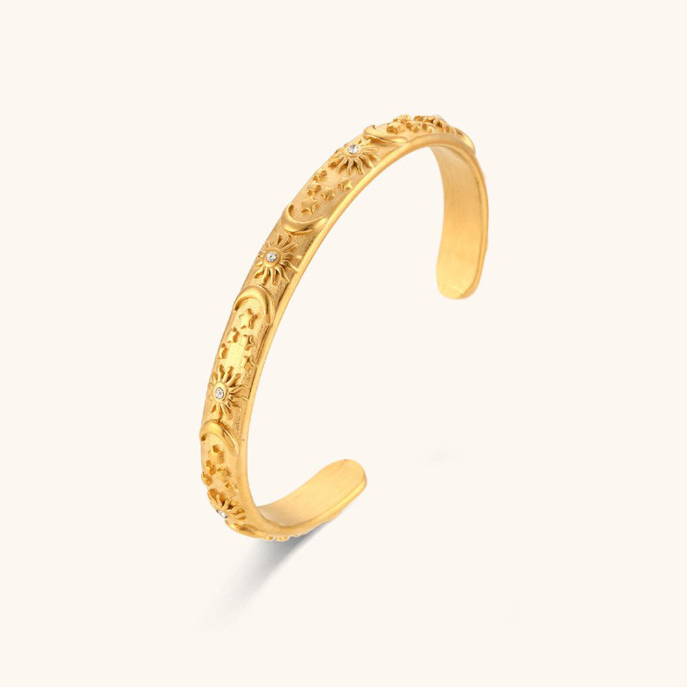 Open-style gold bangle with embossed celestial flowers and boho texture finish