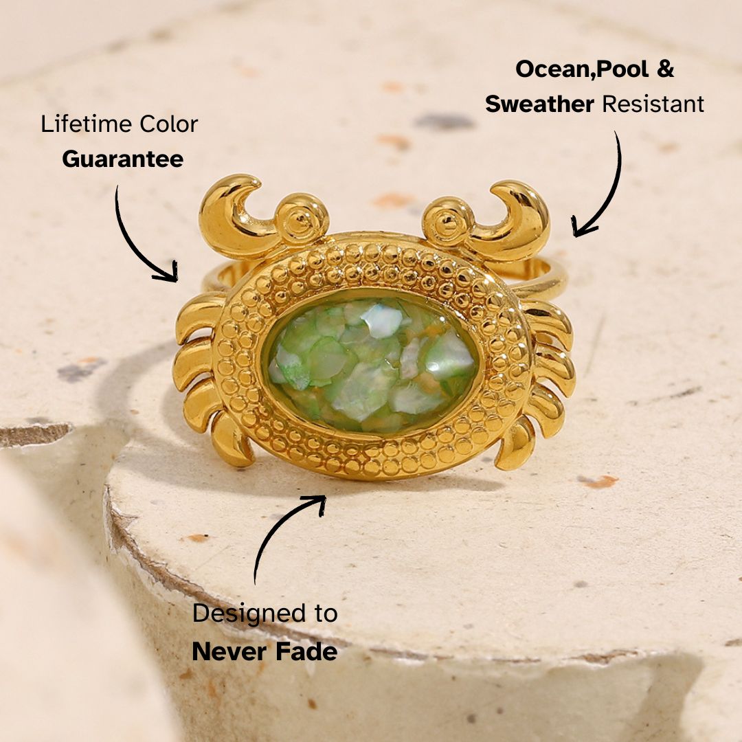 Gold statement ring shaped like a crab, featuring green crushed shell inlay