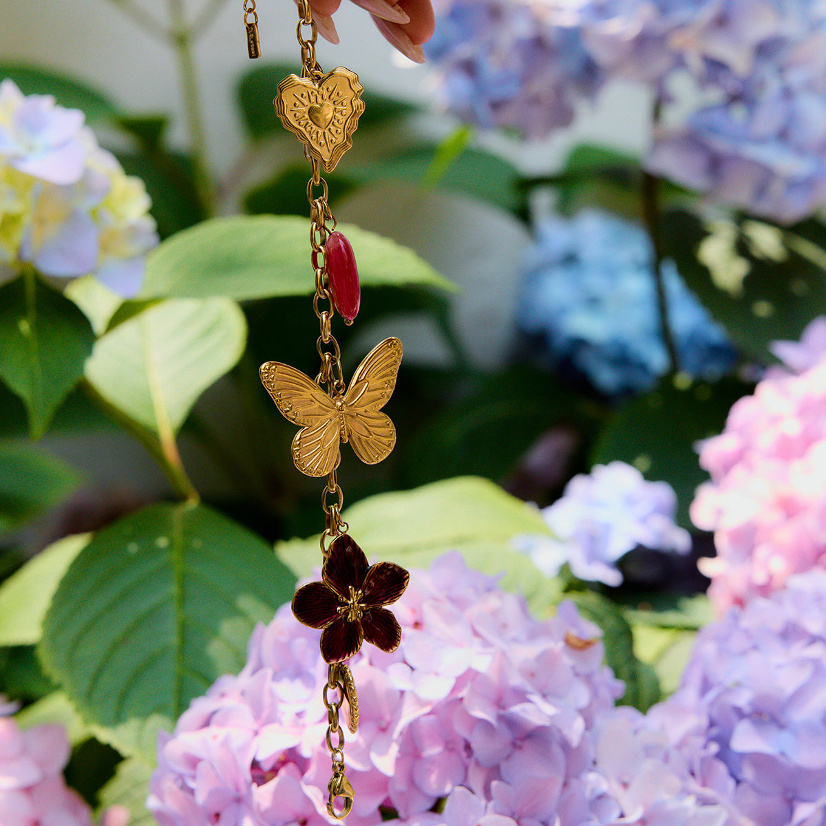 Summer garden shot featuring gold charm bracelet with butterfly design