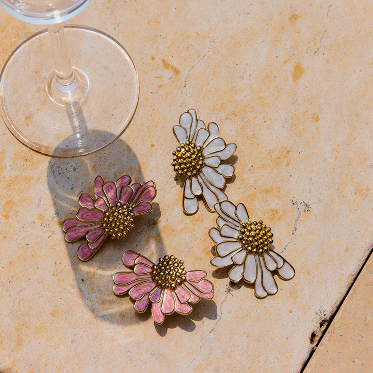 Flatlay of waterproof white daisy studs next to a wine glass