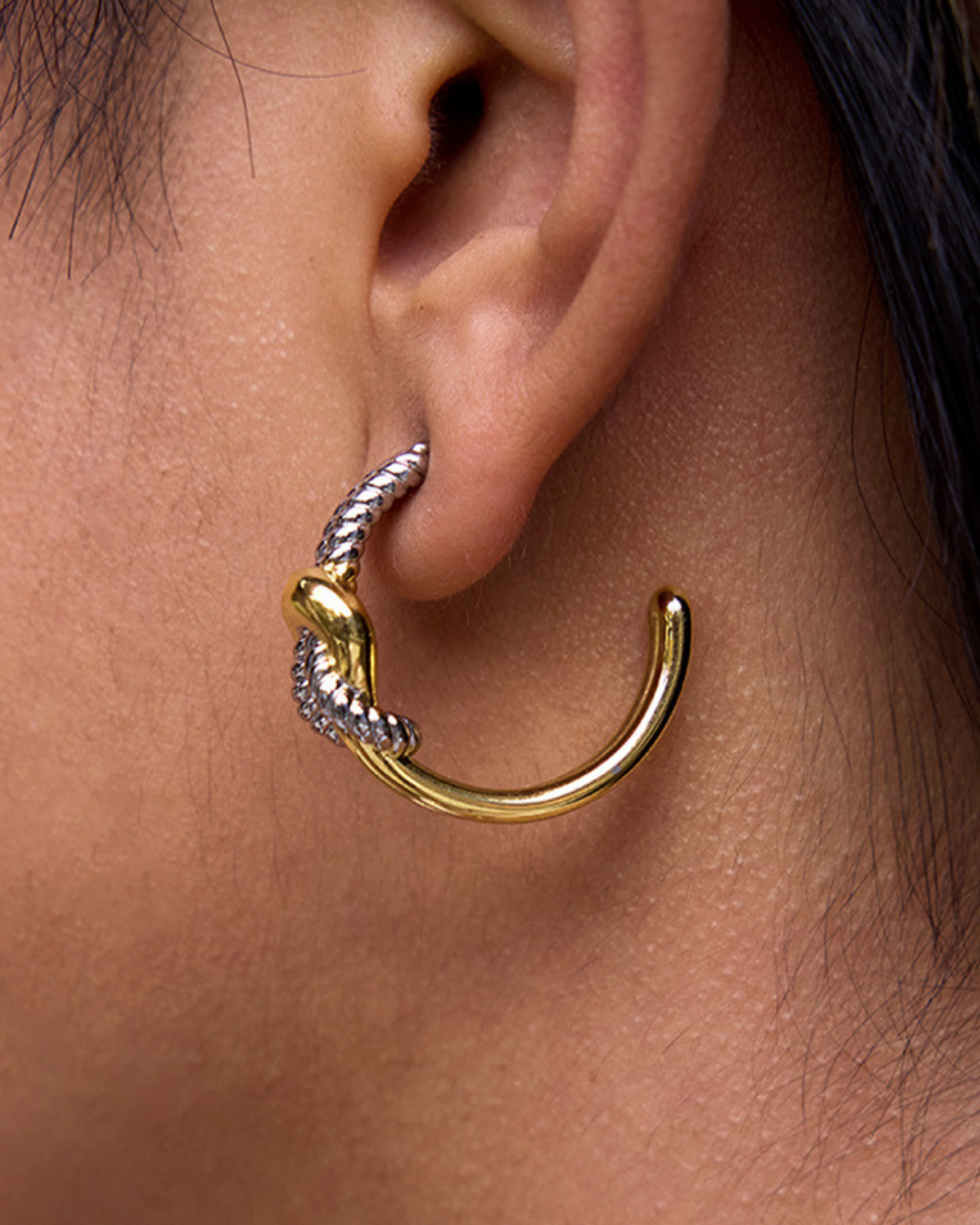 Gold and silver earring worn on an ear
