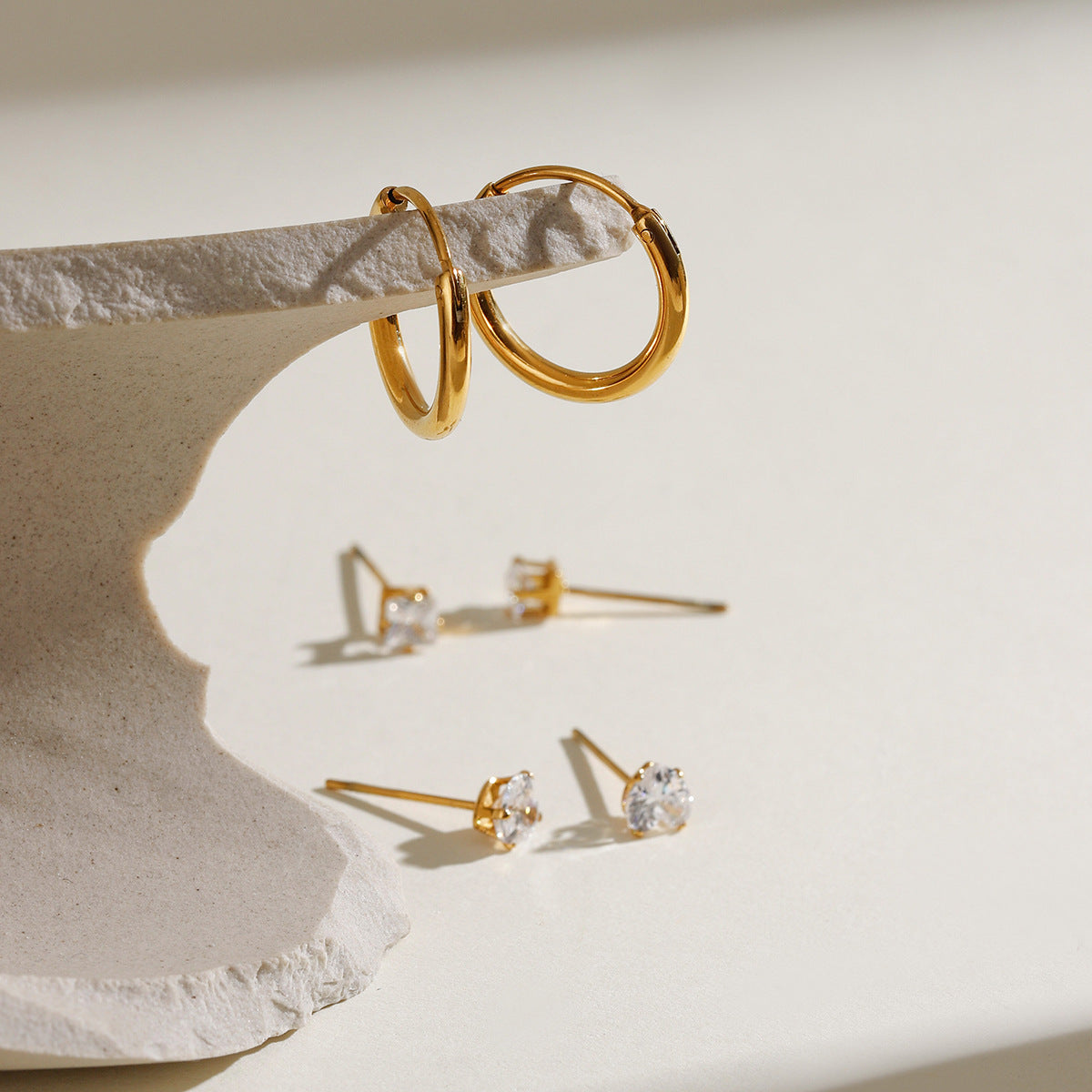 Gold hoop earrings with three different crystal-cut stud designs arranged neatly